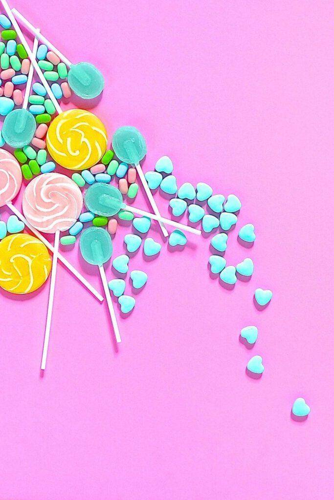 Pastel candies wallpaper with colorful lollipops heart sweets on soft pink background vibrant charm