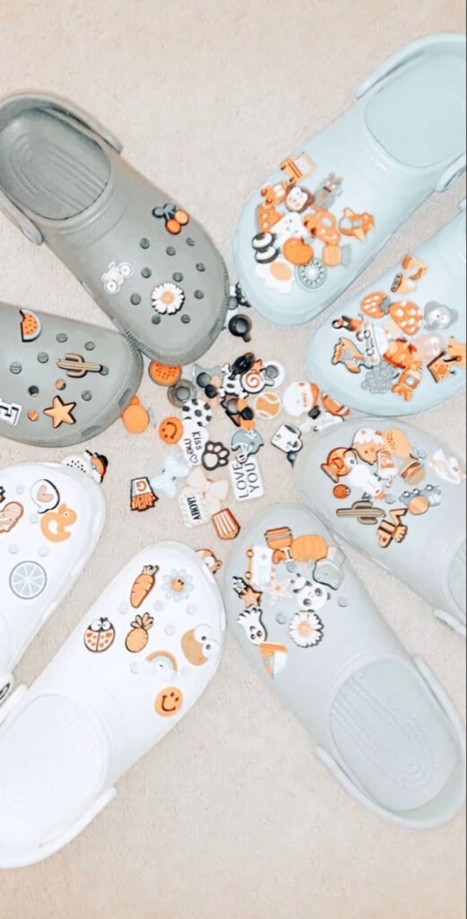 Pastel Crocs circle wallpaper with colorful charms on soft beige background for trendy style