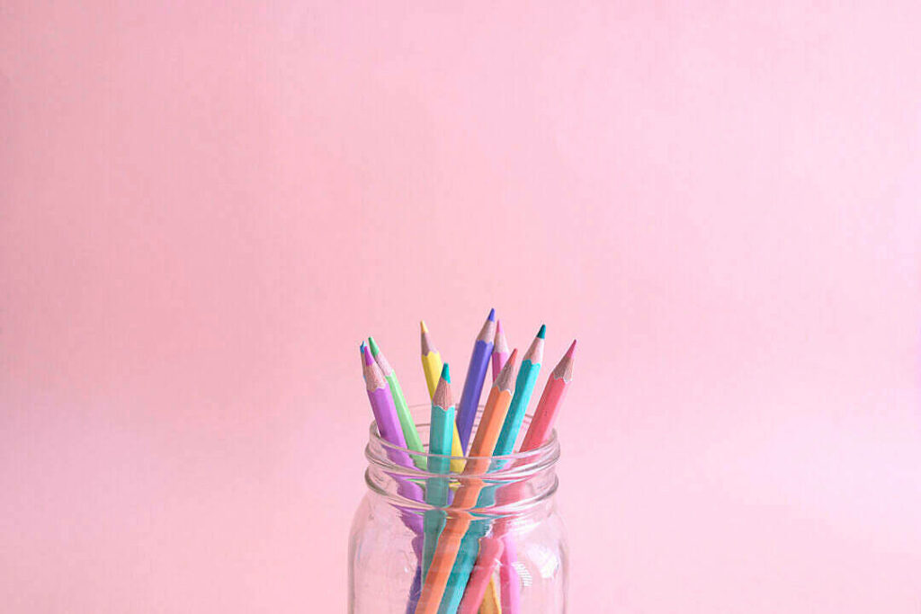 Inspiring Creativity: Pastel Pink Pen Set Shining in Glass Jar on Soft Pink Background Wallpaper