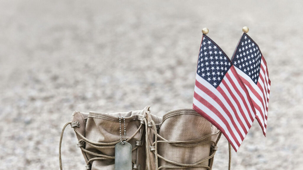 Worn military boots with American flags symbolizing patriotism honoring service members wallpaper