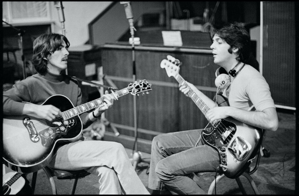 Paul McCartney and George Harrison playing guitars in Beatles recording studio wallpaper background