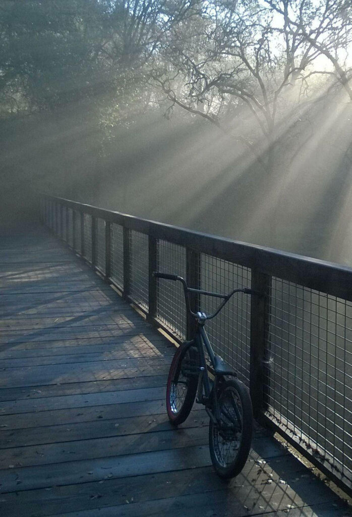BMX bicycle on wooden bridge in soft morning sunlight peaceful atmospheric wallpaper background