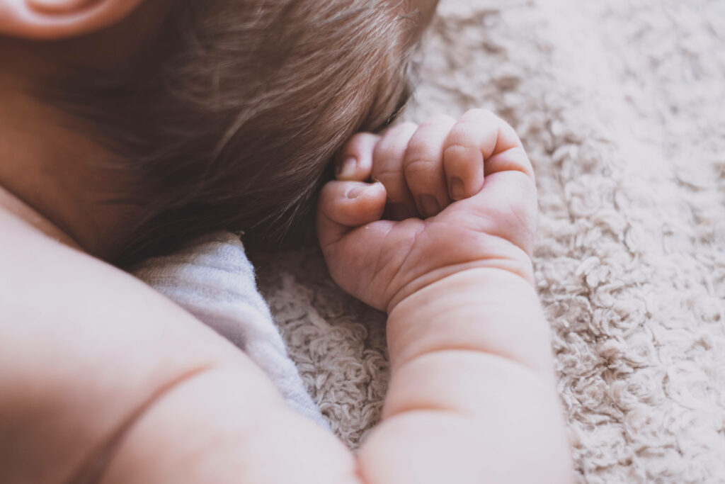 Close-up of peaceful baby boy with smooth white skin resting on soft textured background wallpaper