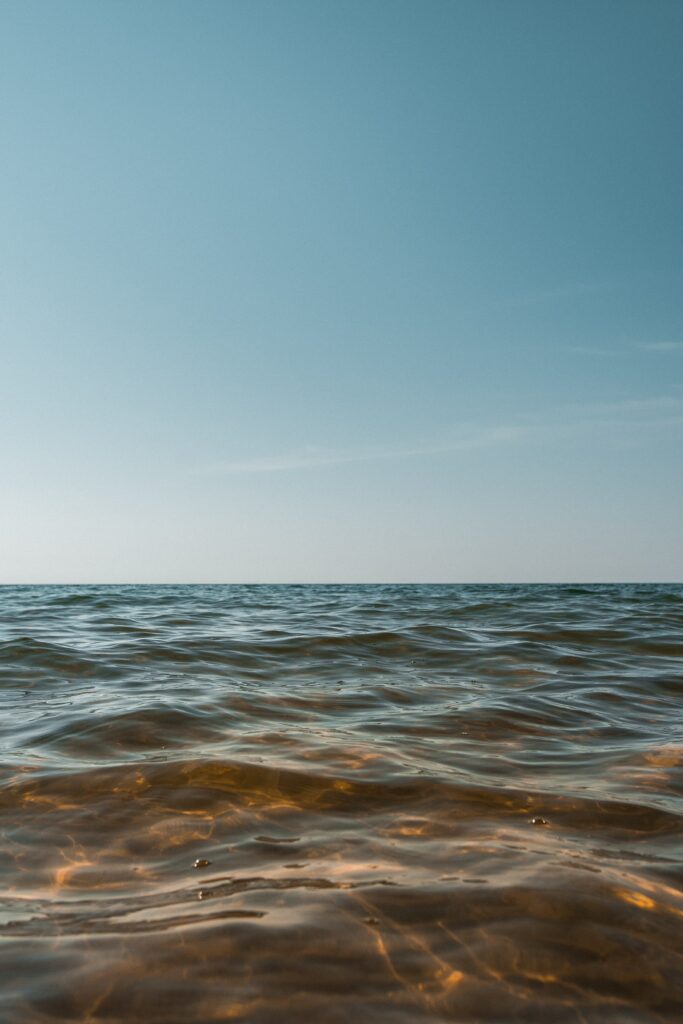 Calm seascape wallpaper with gentle waves glistening under sunlight and clear blue horizon