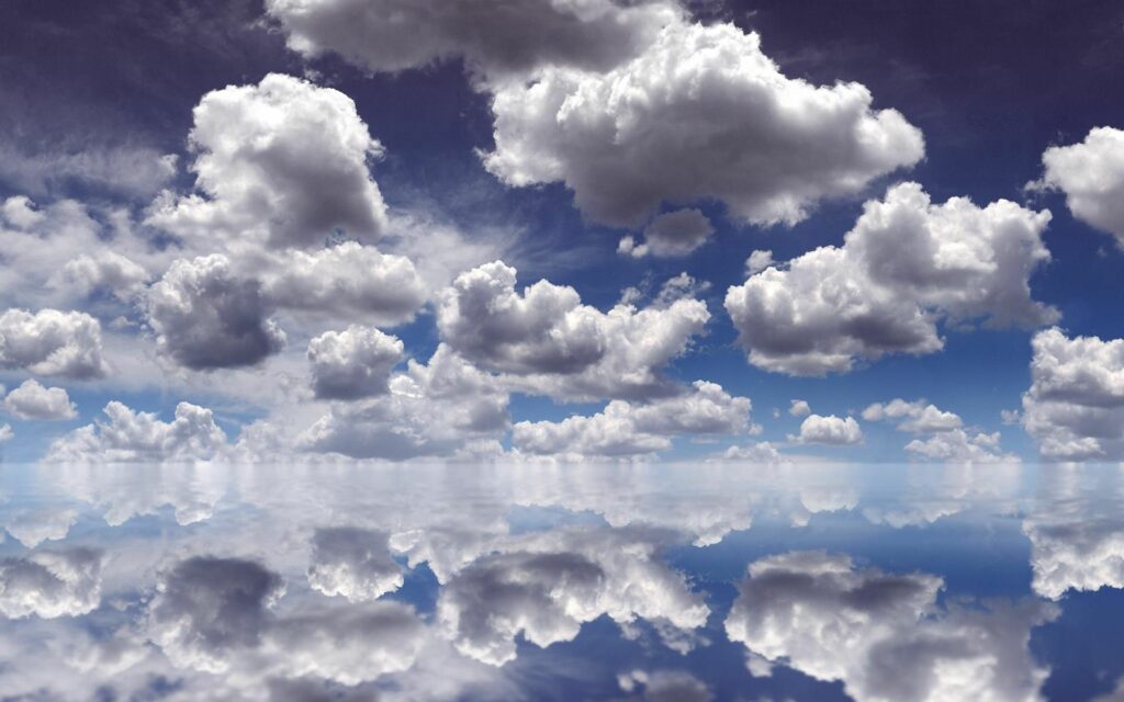 Serene wallpaper with fluffy white clouds mirrored on calm glass-like water under blue sky