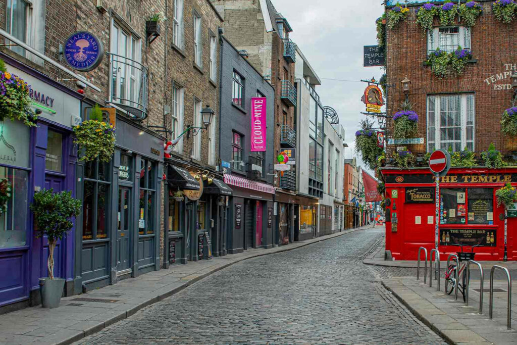 Early morning Dublin cobblestone street with colorful pubs shops under cloudy sky wallpaper