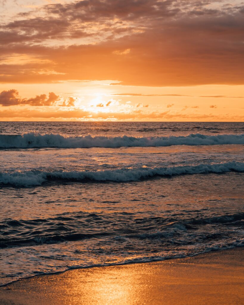 Vibrant coastal sunset wallpaper with golden waves and warm orange amber tones for relaxation