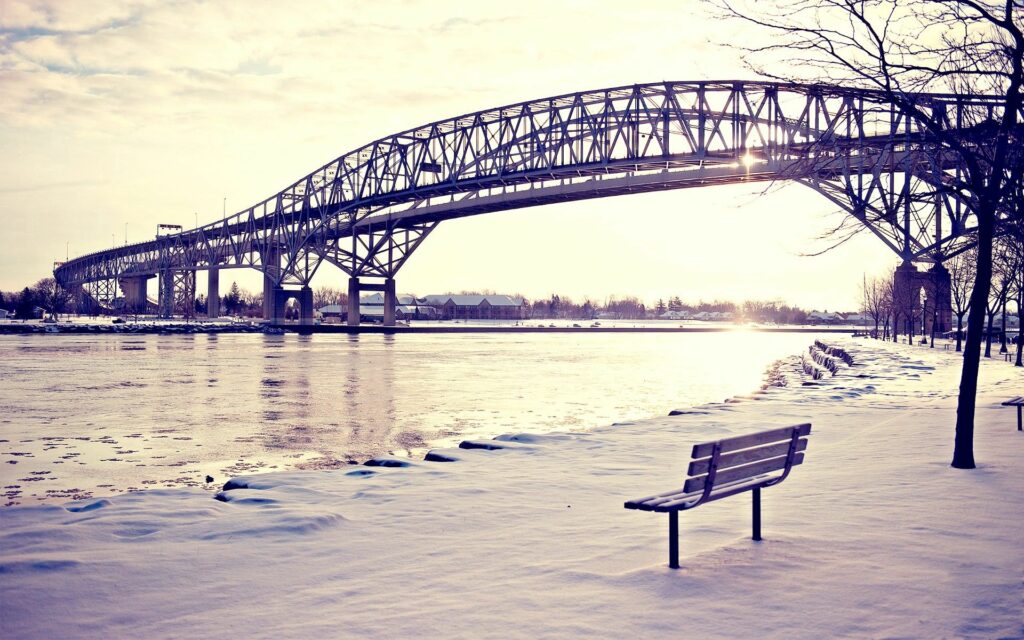 Serene Winter Scene: Snowy Bench & Bridge at Sunset Wallpaper