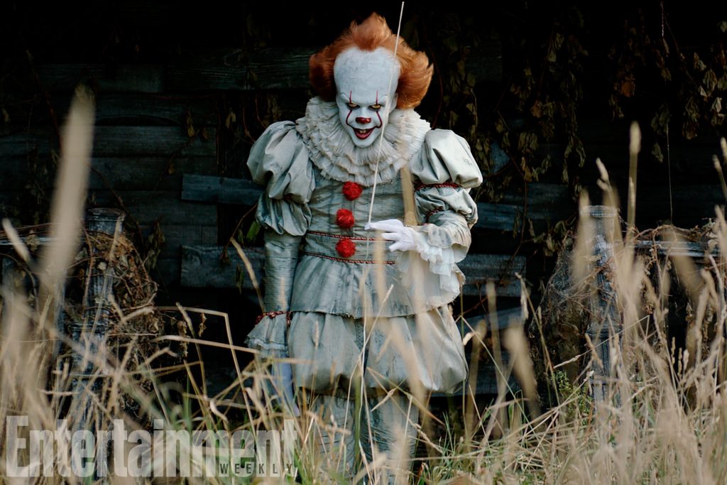 Pennywise the Dancing Clown in grey Victorian costume in dark eerie field horror wallpaper background