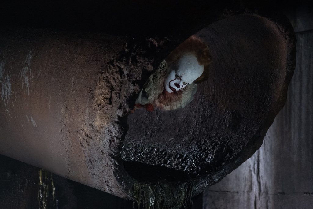 Pennywise the Dancing Clown emerging from rusted sewer pipe scene from 2017 horror film It Wallpaper