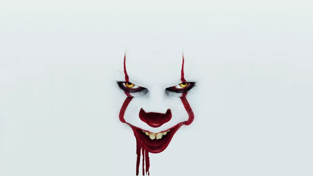 Terrifying Pennywise clown close-up with yellow eyes red makeup and bloodied grin on white background Wallpaper