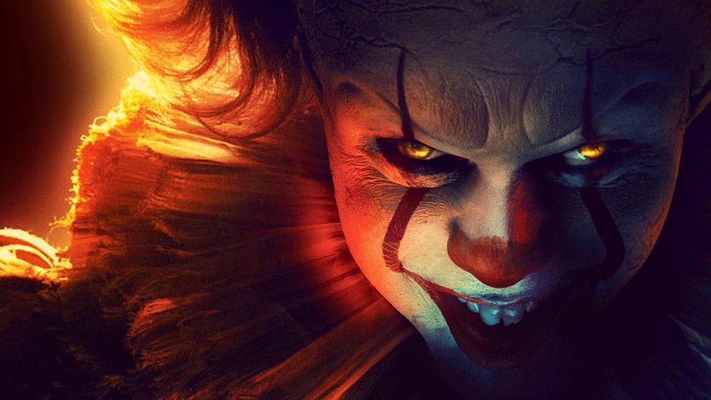 Close-up of Pennywise the Dancing Clown with glowing eyes and sinister grin from 2017 It film Wallpaper