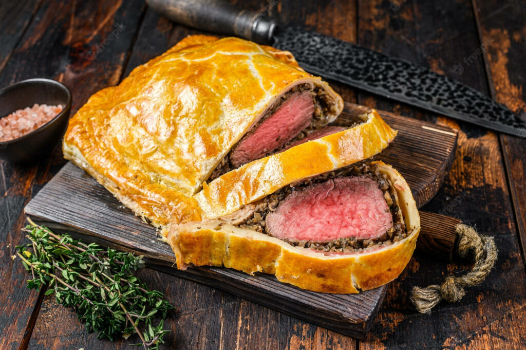 Beef Wellington on rustic board with golden pastry and juicy tender beef center close up wallpaper