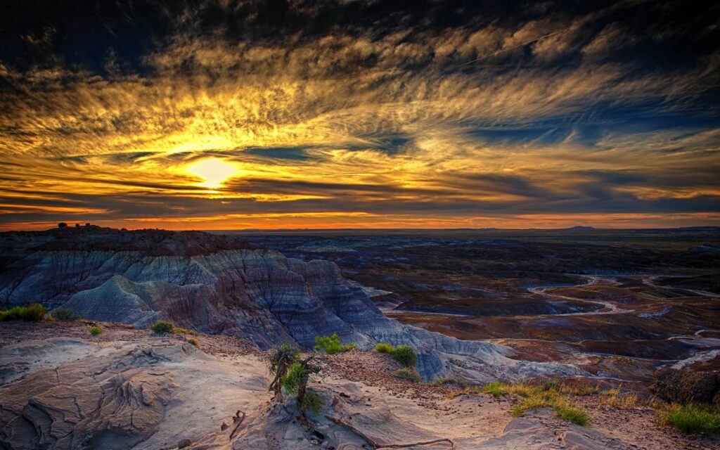 HDR sunset over Arizona Petrified Forest with vibrant orange sky and rugged rock formations Wallpaper