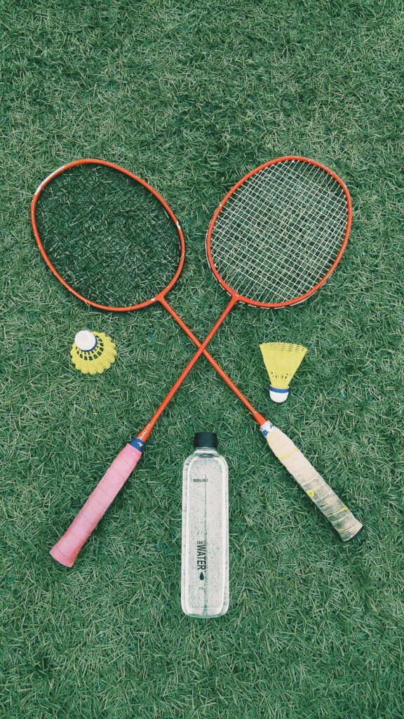 Dynamic Badminton Equipment Set Against Lush Green Field: A Striking Google Background Image Wallpaper