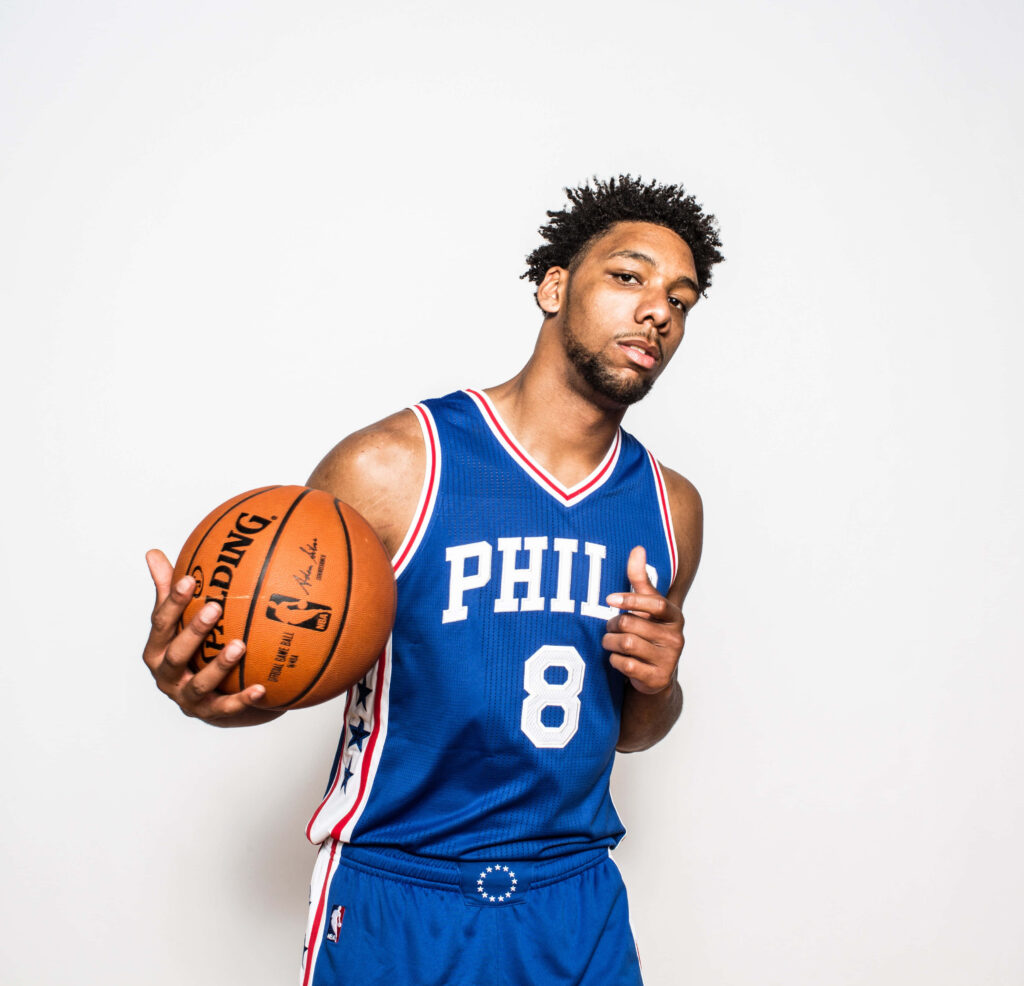 Basketball player in blue Philadelphia jersey holding ball on white background dynamic sports wallpaper