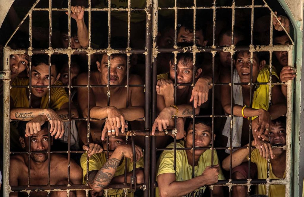 Philippine prison inmates in yellow shirts behind bars gritty documentary photo confinement Wallpaper