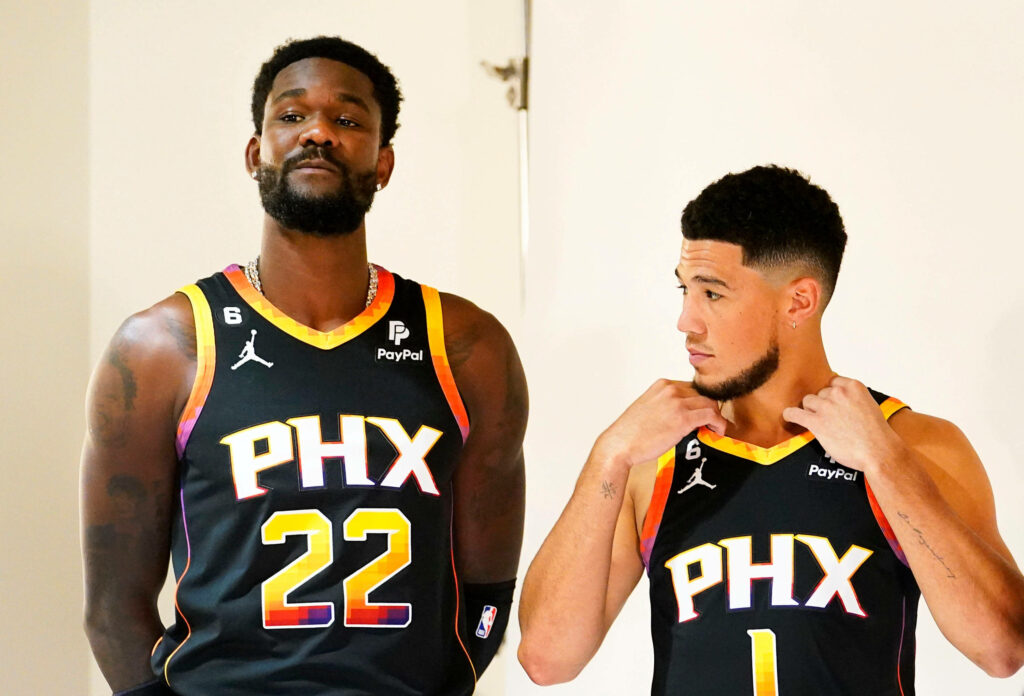 Deandre Ayton and Devin Booker in black Phoenix Suns jerseys dynamic NBA wallpaper background