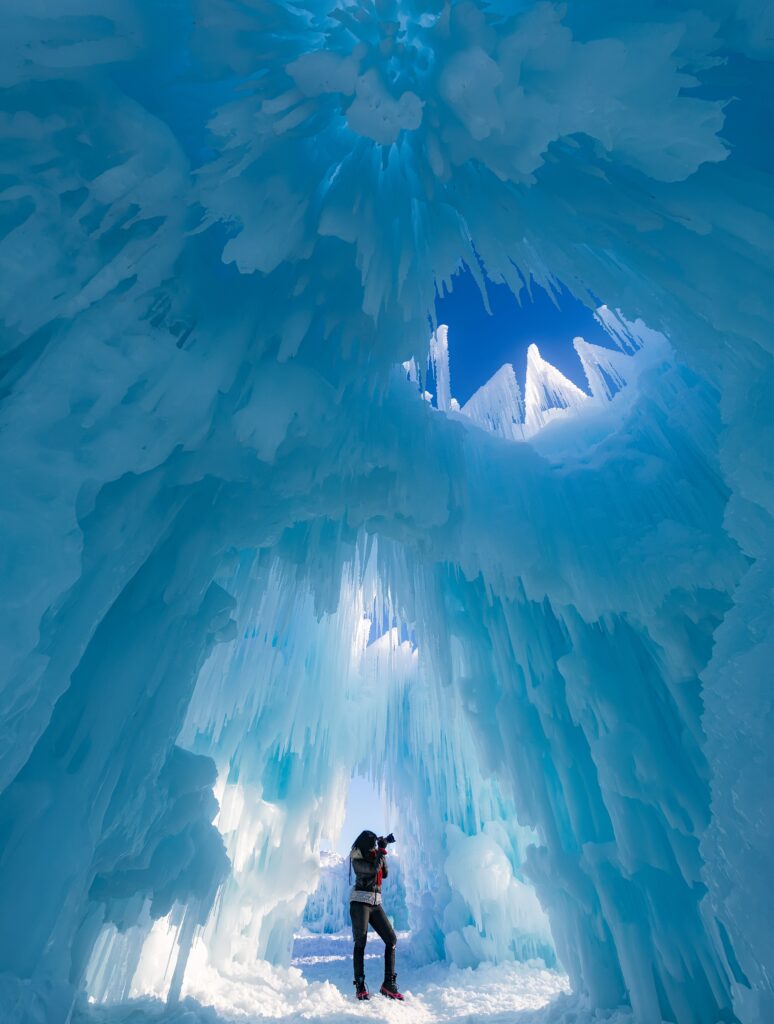 Photographer admiring towering ice formations inside a dazzling glacier with crystalline walls Wallpaper