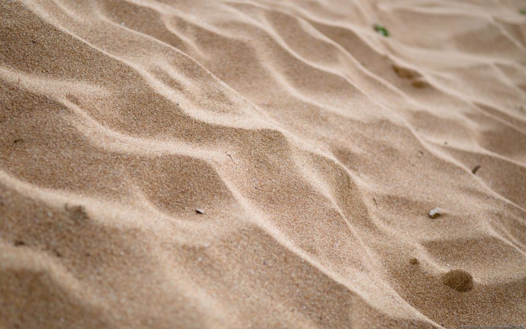Photorealistic sand wallpaper with detailed ripples and natural light highlighting specks of grit