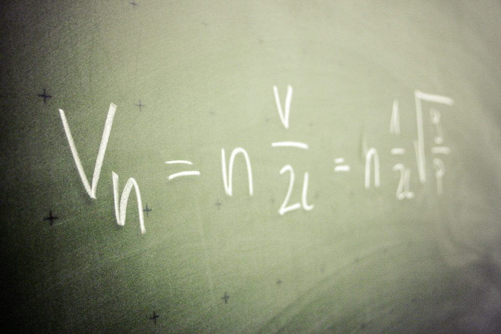 Handwritten harmonic wave physics equation on green chalkboard with shallow depth of field Wallpaper