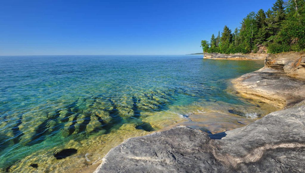 Pictured Rocks National Lakeshore turquoise water rugged sandstone cliffs lush forests blue sky Wallpaper