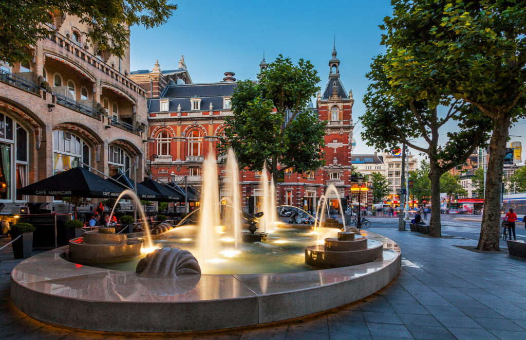 Charming Amsterdam Fountain: Vibrant Trees & Classic Architecture Wallpaper