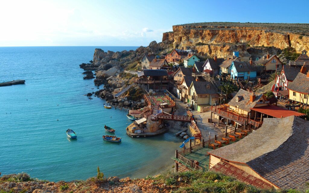 Picturesque Coastal Village Wallpaper: Serene Sea & Rugged Mountains