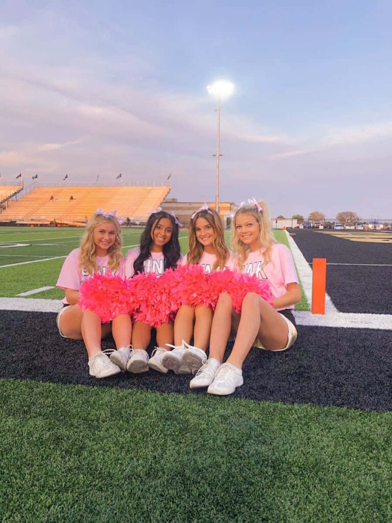 Cheerleaders in Pink Attire with Pom-Poms on Football Field - Wallpaper