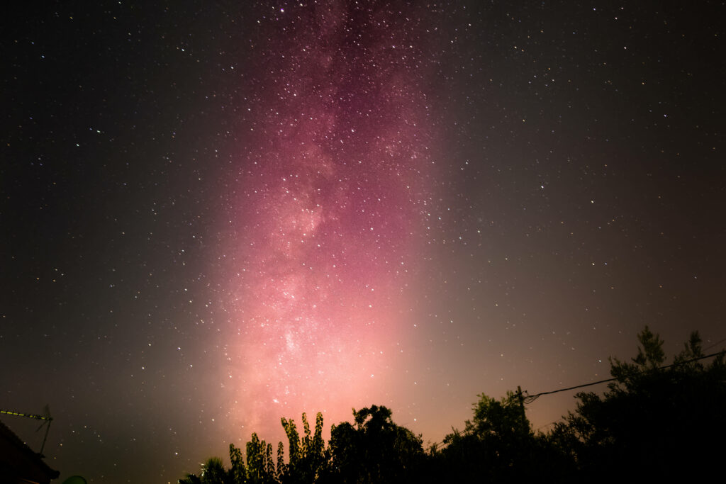 Cosmic Brilliance: A Pink Galaxy Illuminated by Earth's Night Sky Wallpaper