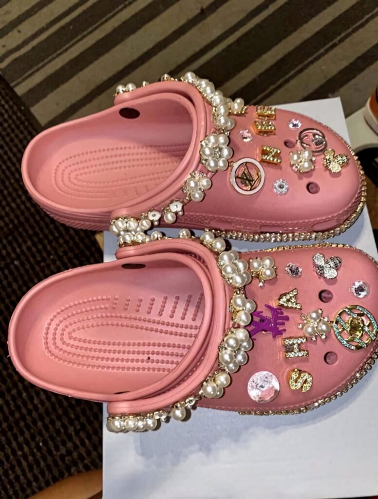 Pink Crocs decorated with rhinestones pearls and charms on neutral background wallpaper