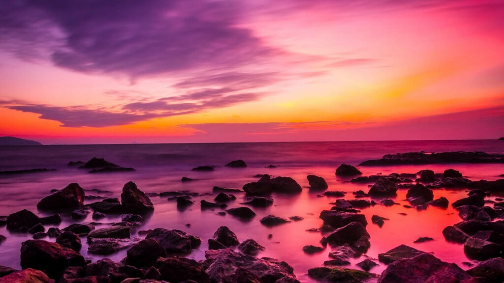 Pink Hued Skyline: Rocks Amidst a Serene Coastal Twilight Wallpaper