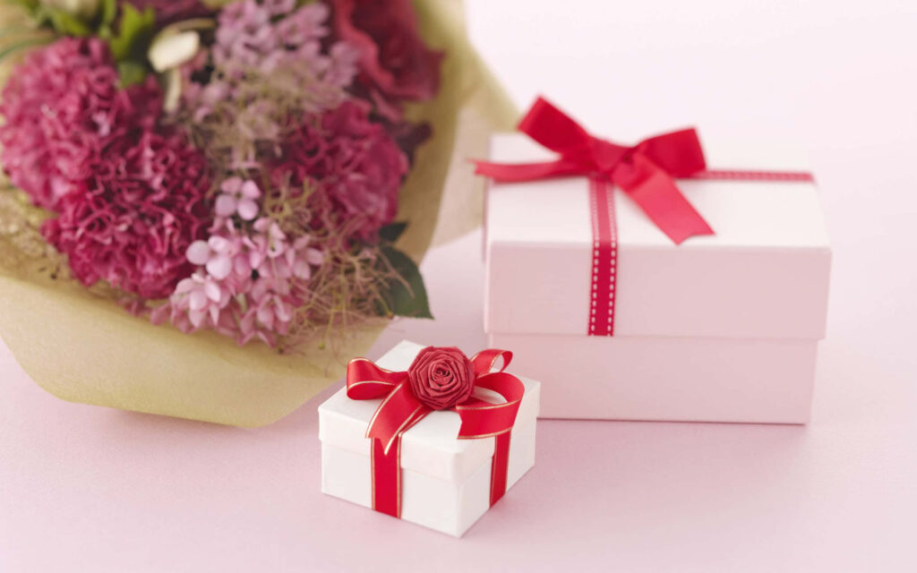 Bouquet of pink and purple flowers with red ribbon wrapped gift boxes on decorative background Wallpaper