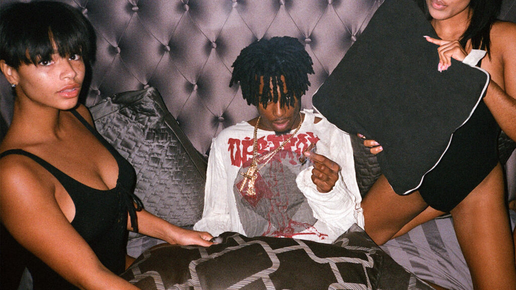 Bedroom Bliss with Playboi Carti: A Wallpaper featuring his PFP joined by two stunning models