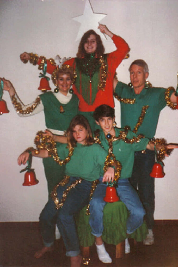 Playful Christmas Family Photo: Human Tree with Tinsel & Lights Wallpaper