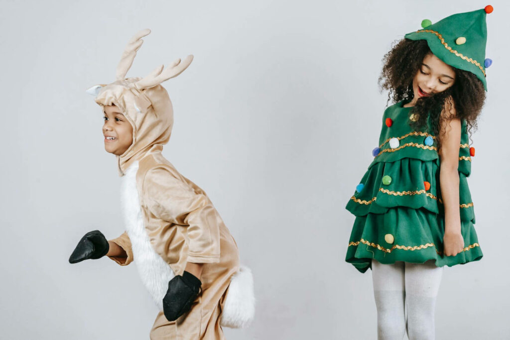 Playful Christmas Wallpaper: Kids in Reindeer & Tree Costumes