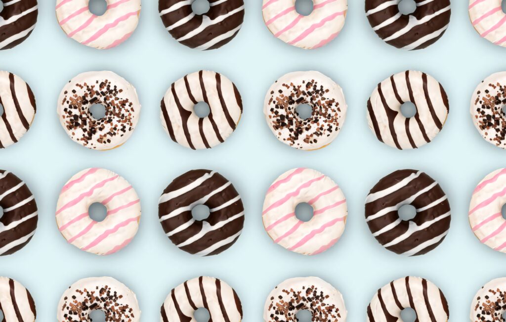 Seamless donut pattern with chocolate and vanilla icing colorful sprinkles on pastel blue background Wallpaper