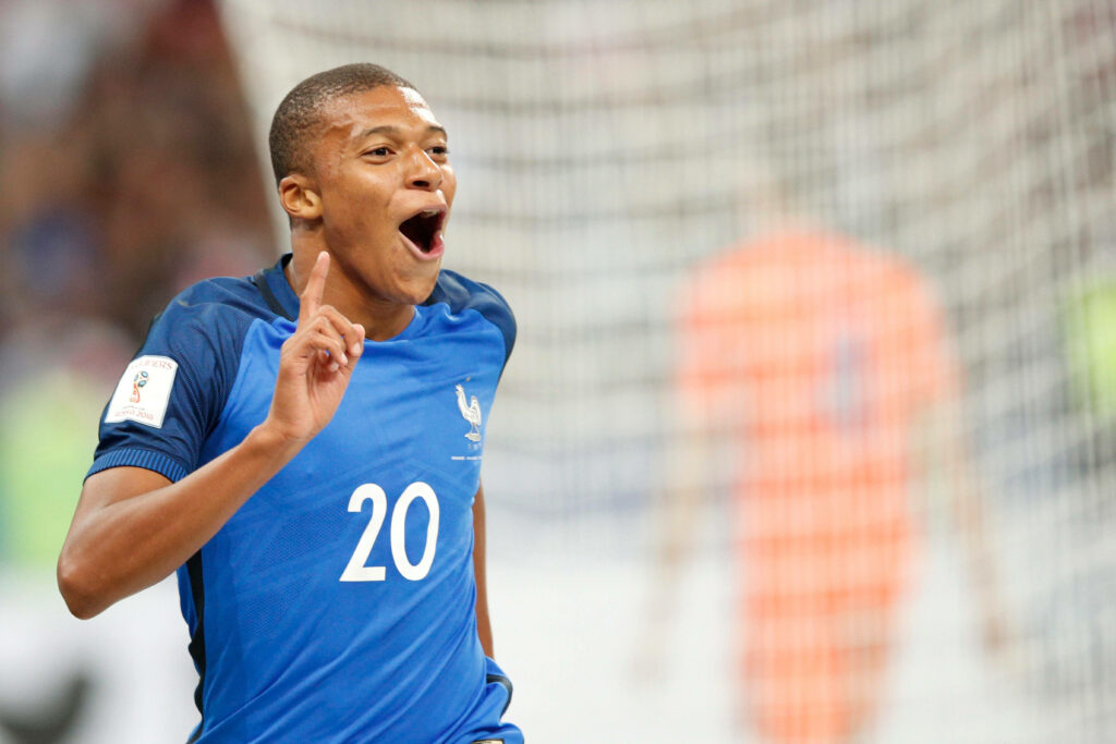 Playful Kylian Mbappe Wallpaper: Dynamic Football Charisma