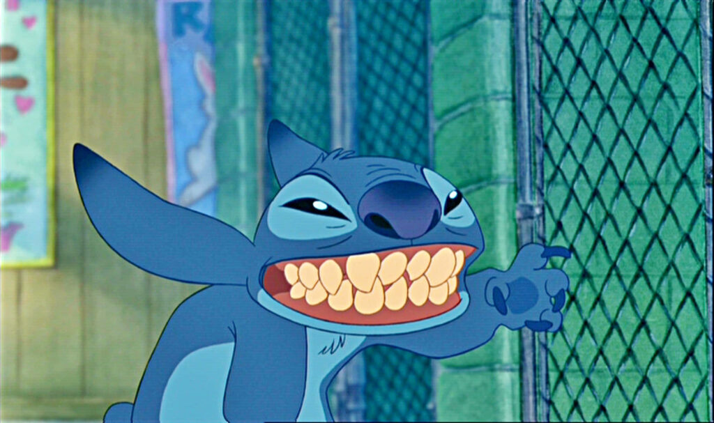 Playful Stitch Wallpaper: Grinning Character Against Colorful Fence