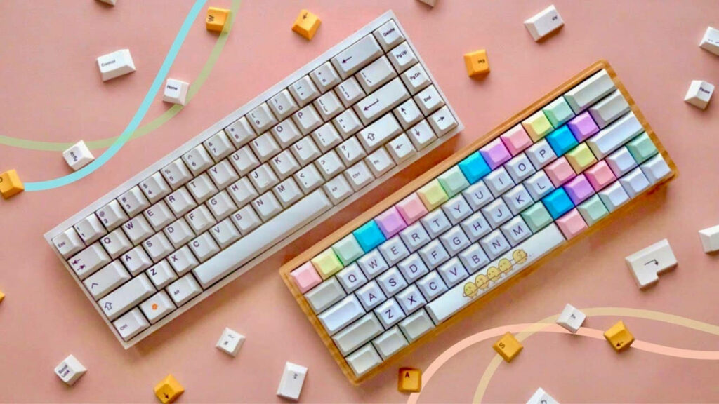 Keyboard Heaven: An Alluring Pastel Flat Lay of Mechanical Keyboards and Keycaps on Pink Wallpaper