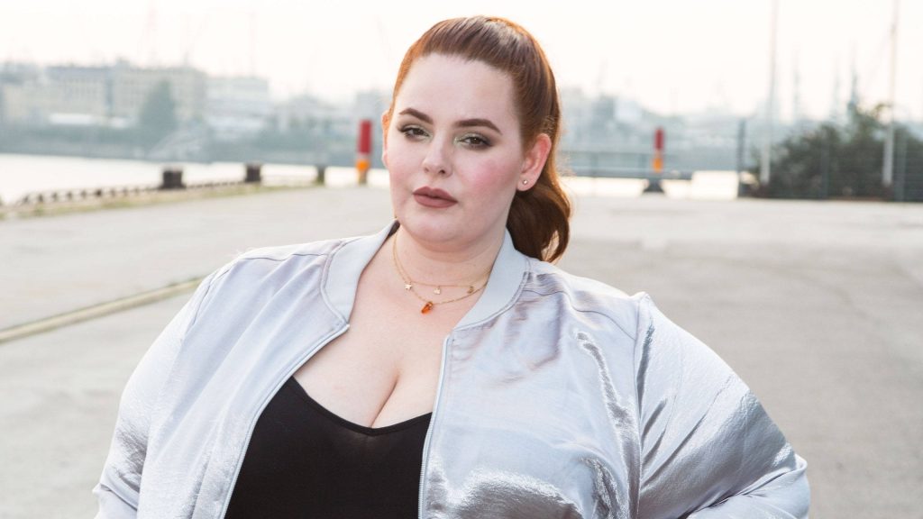 Plus-size model Tess Holliday in metallic silver bomber jacket by industrial waterfront background Wallpaper
