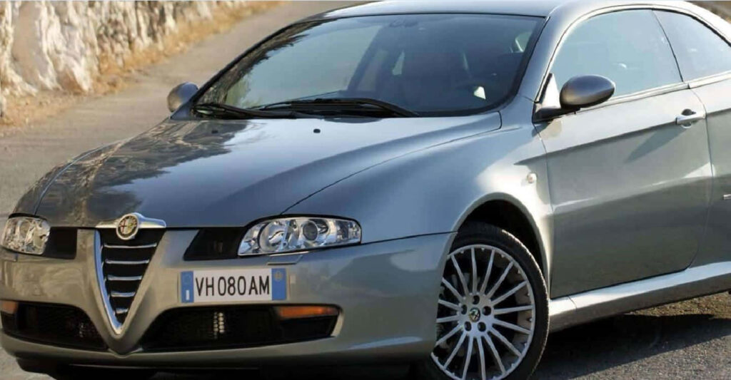Silver Alfa Romeo GT cruising sunlit road showcasing elegant curves and signature grille wallpaper