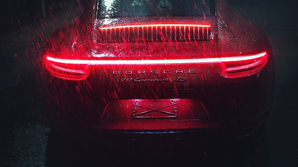 Porsche 911 Carrera 4 GTS rear profile with neon red light bar in rainy moody dark background wallpaper