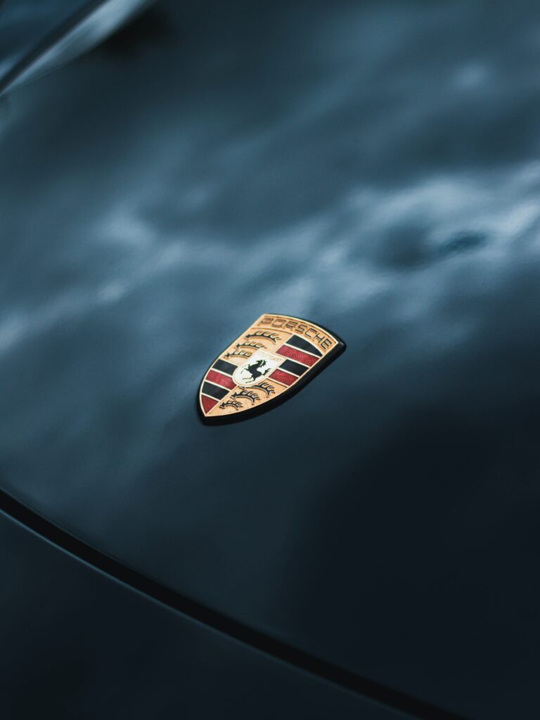 Close-Up of Iconic Porsche Logo on Sleek Sports Car Hood Wallpaper