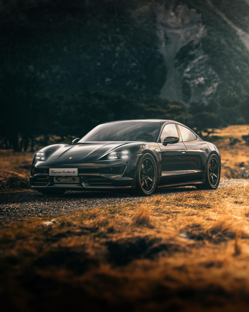 Porsche Taycan Turbo S driving through rugged landscape showcasing sleek electric sports car design Wallpaper