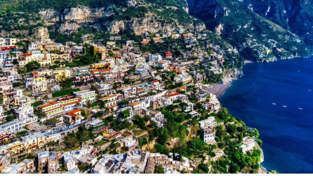 Drone view of colorful Positano cliffside buildings Amalfi Coast lush hills and blue sea wallpaper