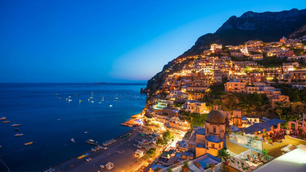 Positano Amalfi Coast night lights wallpaper with colorful hillside buildings reflecting on calm sea