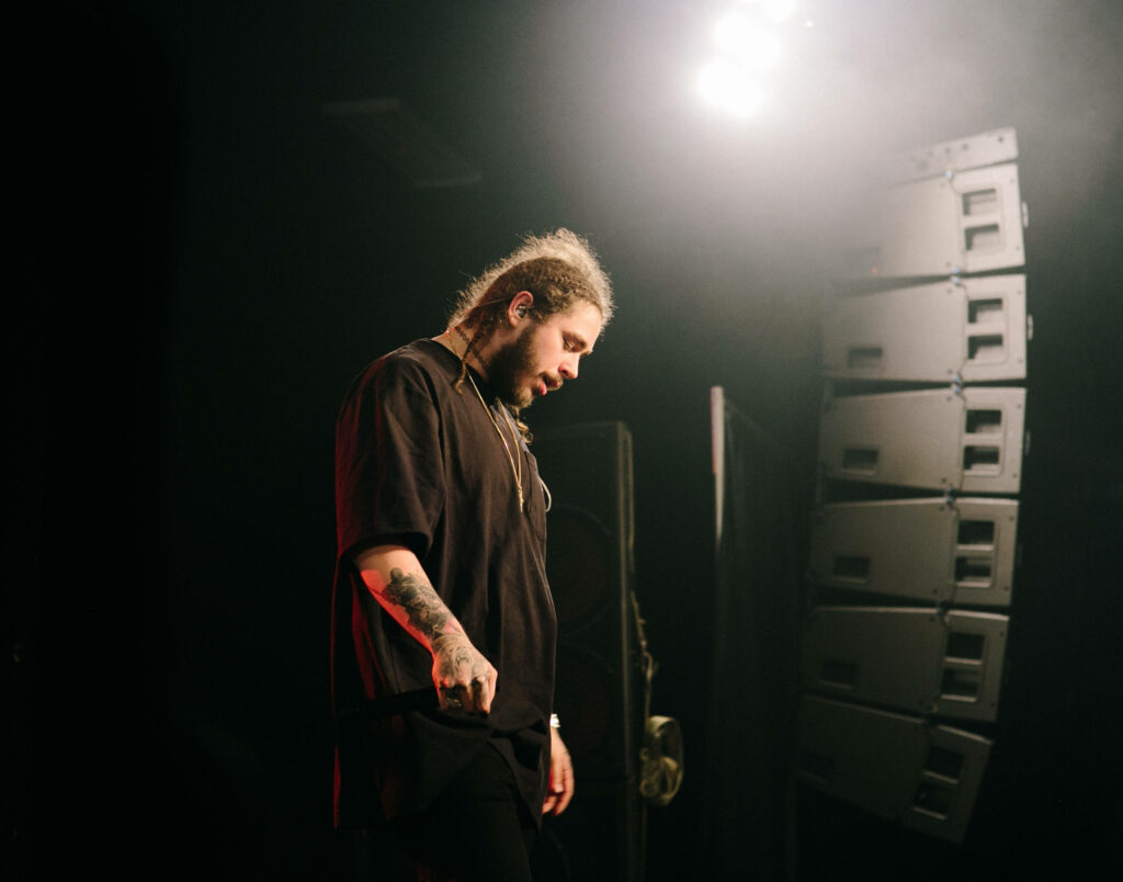 Post Malone: Dynamic Stage Performance with Signature Style Wallpaper
