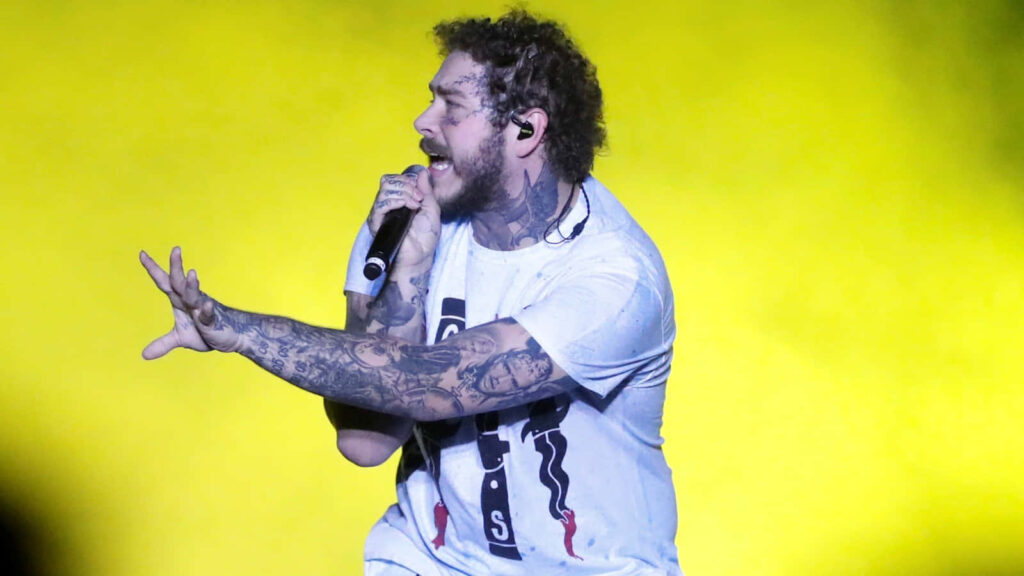 Vibrant Post Malone Wallpaper: Passionate Performance on Yellow Background