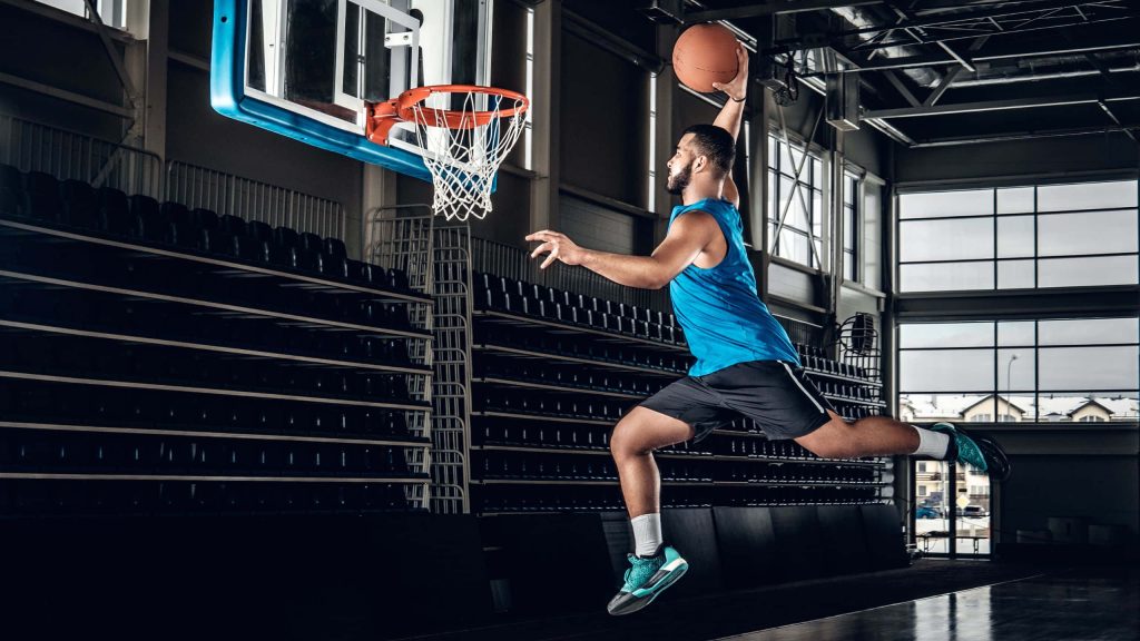 Bearded basketball player slam dunk in empty indoor arena with dramatic lighting and high contrast Wallpaper